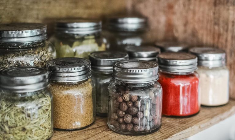 A row of spices in sealed containers on a shelf