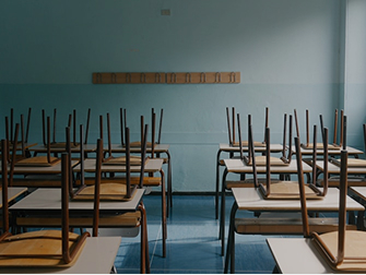 Empty classroom with chairs stacked upside down on desks in neat rows