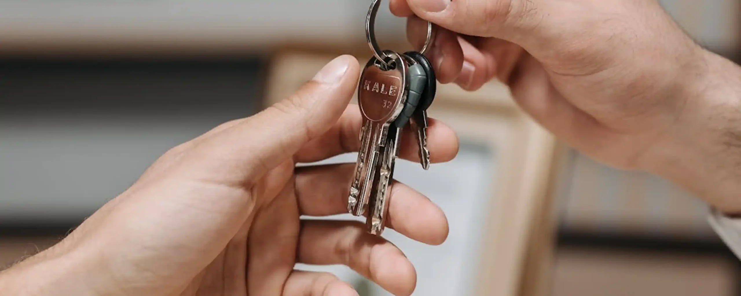 Two hands exchanging a metal keyring with several keys